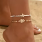 A Set of Two Women'S Anklets Featuring a Summer Ocean Theme with Starfish And Turtle Designs in Brown, White, And Beige Beads.